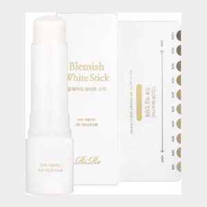 RiRe Blemish White Stick white twist-up stick beside its white and gold box and skin tone chart